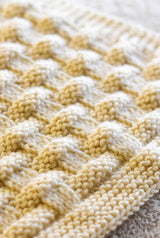 Close up of cream colored blanket showing garter stitch border and highly textured blanket body.  thumbnail
