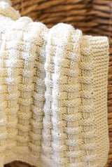 Textured cream blanket draped over dark wicker basket. thumbnail