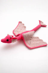 Crochet dragon with a long body and no back legs on a white background. The dragon body is bright pink and has paler pink wings and tail fin, ears, and tiny horns.  thumbnail