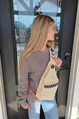 Side view of woman wearing crochet sling bag. The bag has a side panel to make it deeper and a button to hold the larger pocket closed.  thumbnail