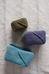 Top down view of three crochet baskets in varying sizes, laid on white fur blanket.  thumbnail