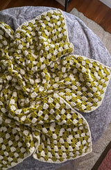 Crochet afghan in chartreuse and cream sits on top of a grey footstool.  thumbnail