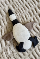 Stuffed goose lays on its back to show white belly and chin, black neck, and black feet attached above tail.  thumbnail