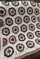 Crochet blanket made of hexagonal motifs in cream, dark brown, medium brown, and tan.  thumbnail