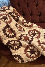 Crochet blanket draped over arm of plush armchair.  thumbnail
