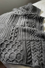 Close up of grey knit afghan with different cabled sections.  thumbnail
