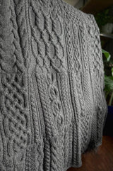 Afghan draped over rack to show cabled patterns, knit in sections and seamed together.  thumbnail