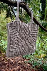 Tote bag hangs from branch in conifer forest. thumbnail