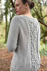 Side back view of pale grey cardigan, showing raglan lines and cable pattern on back.  thumbnail