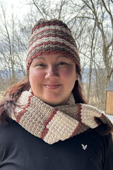 Woman in a black shirt wears a crochet scarf and matching hat. The Hat has narrow stripes of cream, taupe, brown, and rusty red. The scarf has larger blocks of the same colors.  thumbnail