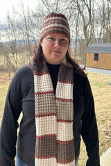 Woman wears a crochet hat and a matching scarf, which is long enough to hang past the waist when unwrapped.  thumbnail