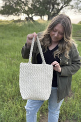 Woman holds rectangular tote bag by straps, which are long enough to wear on the shoulder. thumbnail