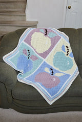 Apple afghan laid on couch indoors.  thumbnail