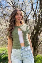 Woman wears a green short sleeve cardigan buttoned only at the top. It has horizontal textured bands.  thumbnail