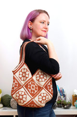 Crochet patchwork bag work over the shoulder of woman in black short with lilac hair.  thumbnail