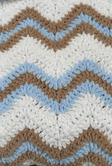 Extreme close-up of ripple texture on blanket. The design has wide stripes of white with narrow stripes of warm tan brown and sky blue.  thumbnail
