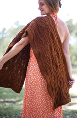 Woman wears rectangular wrap draped over one shoulder. The wrap comes down to mid-thigh in both front and back.  thumbnail