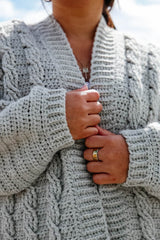 Close up of front of cardigan, showing ribbed front bands and crochet front panels. The sleeves are wide and have a ribbed cuff.  thumbnail