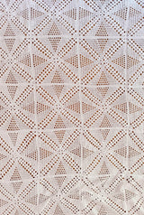 Top down view of crochet coverlet made of individual blocks. The blocks combine to make a diamond pattern with openwork mesh.  thumbnail