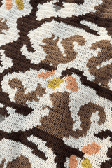 Close up of crochet blanket, focusing on an adult squirrel and smaller squirrel in light brown, sitting on a darker brown branch, under yellow and orange leaves.  thumbnail