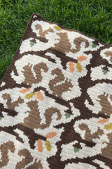 View of corner of crochet afghan, laid on grass.  thumbnail