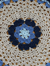Close up of the center of doily. It is light blue in the middle, then medium blue, then dark blue, then a large section of cream/beige.  thumbnail