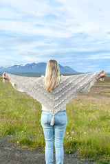 Woman stands with her back to camera, holding shawl with arms outstretched.  thumbnail