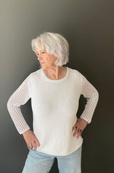 Front view of woman wearing a knit white long sleeve tee and pale jeans.  thumbnail