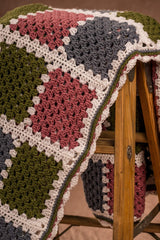Close up of crochet afghan folded on wooden step ladder.  thumbnail