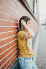 Side view of crochet lace top, worn by woman leaning against brick building.  thumbnail