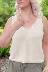 Front view of a woman wearing a cream tank top with khaki bottoms. The tank top is knit with medium width straps and a shallow v-neck.  thumbnail