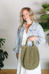 Full view of woman holding crochet bag by short handles.  thumbnail