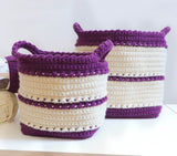 Two crochet baskets, with smaller one in front of larger one. The baskets are cream and purple.  thumbnail