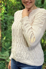 Cropped side view of cream knit sweater, showing drop shoulder and plain sleeve against cabled front.  thumbnail