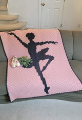 Crochet afghan draped over the couch, with a pair of ballet slippers and a bouquet.  thumbnail