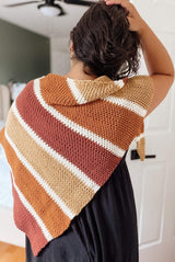 Back view of woman wearing striped shawl over a black dress. The shawl is an asymmetric triangle with larger stripes separated by smaller cream stripes.  thumbnail