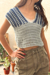 Front view of woman wearing crochet top with a deep V neck, with a white camisole underneath and olive pants.  thumbnail