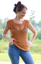Front view of woman wearing summer top with a camisole underneath, and blue jeans. The crochet top is a golden orange and has a variety of stitch patterns.  thumbnail