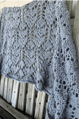 Close up of knit shawl draped over a worn wooden fence.  thumbnail