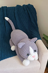 Top view of crocheted cat, with legs tucked close to body and tail upright. thumbnail