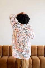 Back view of crochet cardigan. It goes to the model's knees and has a ribbed bottom band and slightly cropped sleeves.  thumbnail
