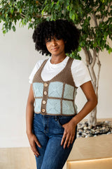 Front view of crochet vest worn over a white tee and jeans. The model stands in a studio setting in front or a potted tree.  thumbnail