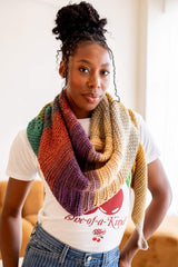 Woman in a graphic tee and striped jeans wears a shawl wrapped kerchief style around her neck.  thumbnail