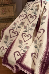 Crochet afghan with embroidered details draped over chair.  thumbnail