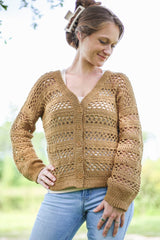 Woman in a yellow crochet long-sleeved cardigan and blue jeans standing in a grassy yard.  thumbnail