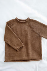 Flat lay of child's sweater on white background. It has a short funnel neck, commercial style raglan shaping, long sleeves, and rolled hems.  thumbnail