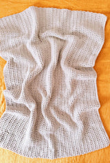 Top down view of pale crochet blanket laid on saffron background.  thumbnail