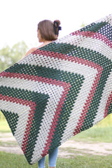 Woman holds afghan open over her back, showing off chevron stripe pattern.  thumbnail