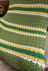 Crochet blanket in olive green with smaller bands of white, yellow, and kelly green.  thumbnail