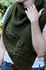 Cropped front view of woman wearing dark green shawl over a white t-shirt and jeans. The shawl has a wide cabled border.  thumbnail